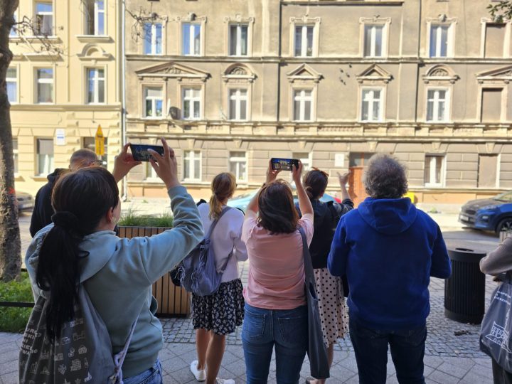 Grupa ludzi fotografująca zabytkową kamienicę