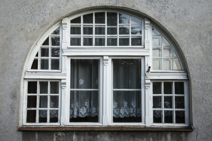 Zdjęcie dużego, dzielonego, półokrągłego drewnianego okna, pomalowanego na biało.